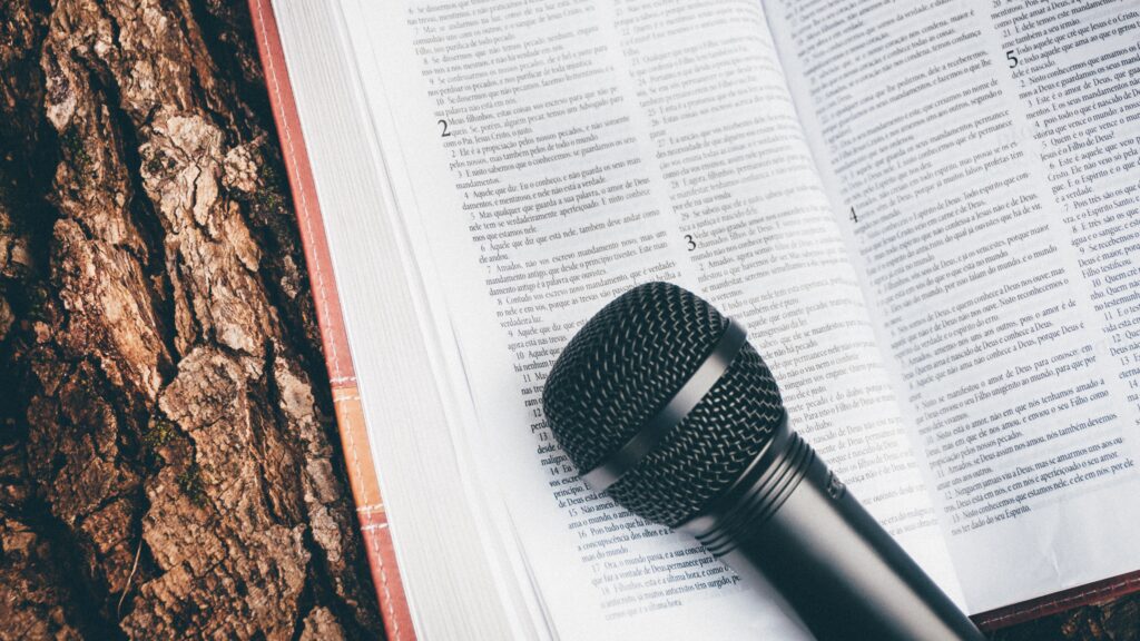 an open bible resting on a tree, with a microphone on it