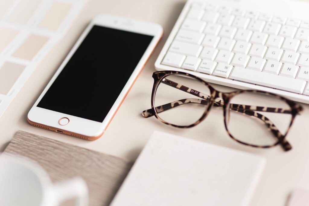 a phone and glasses beside a laptop