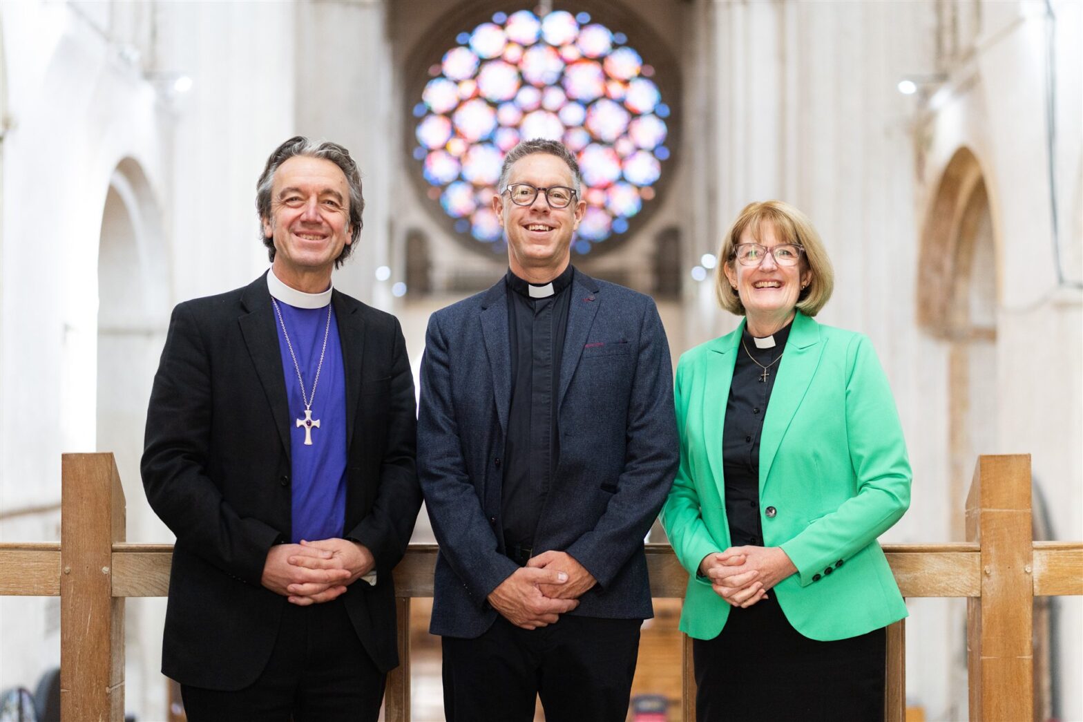 Bishop Andrew Rumsey, Tim Lomax, and Dean Jo Kelly-Moore pictured in front of the Rose Window at St Albans Cathedral